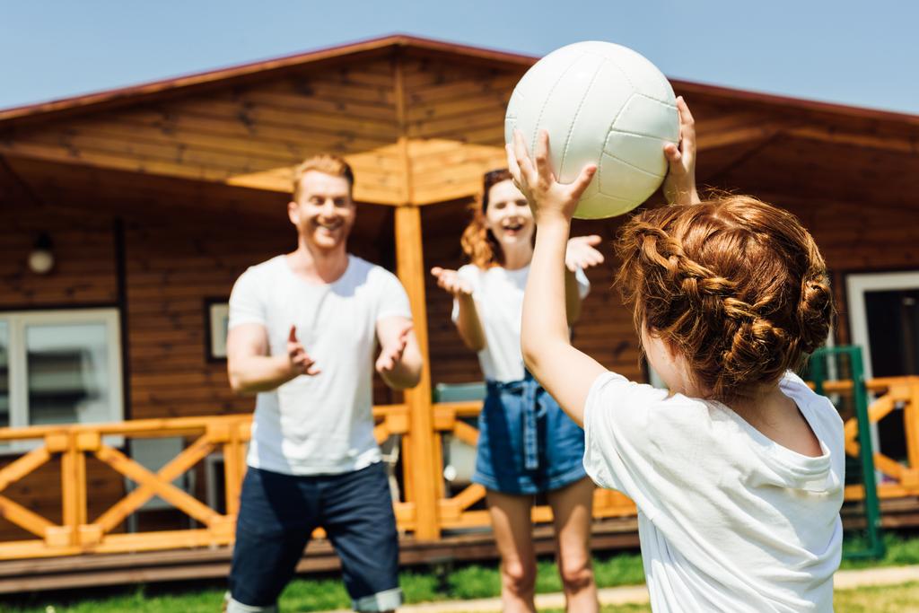 маленька дівчинка грає у волейбол з батьками в саду
 - Фото, зображення
