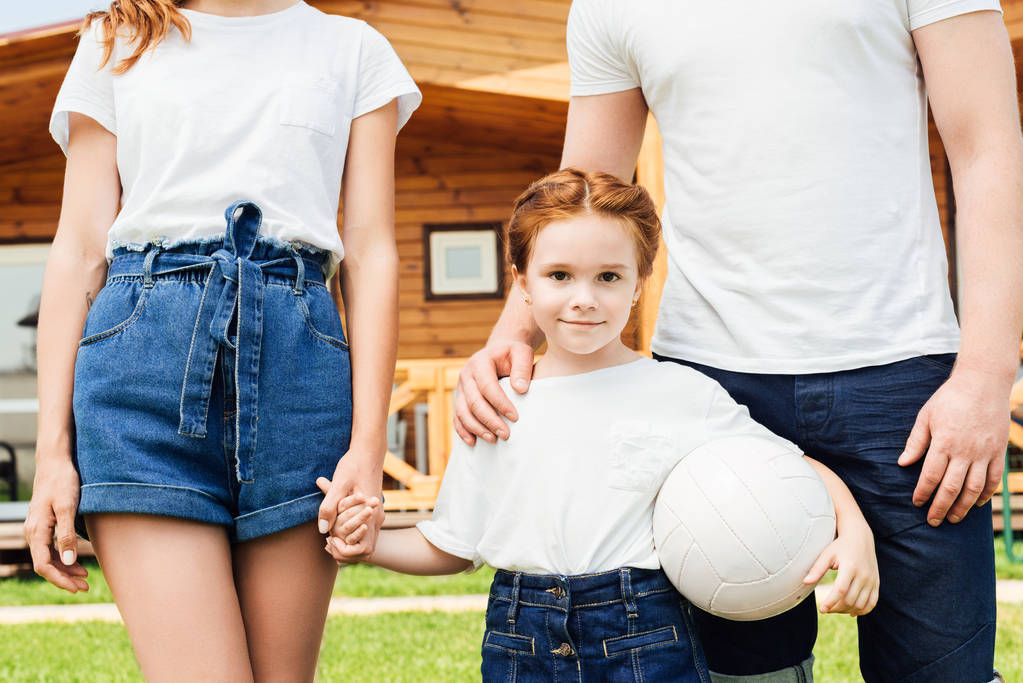 roztomilá malá holčička se svými rodiči držení míče volejbal a při pohledu na fotoaparát - Fotografie, Obrázek
