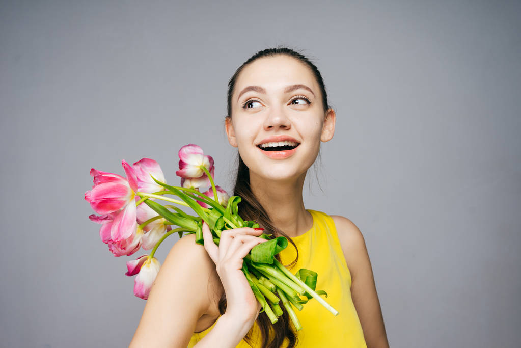 黄色のドレスで幸せな笑みを浮かべて少女は香りのよい花とポーズの花束を保持します。 - 写真・画像