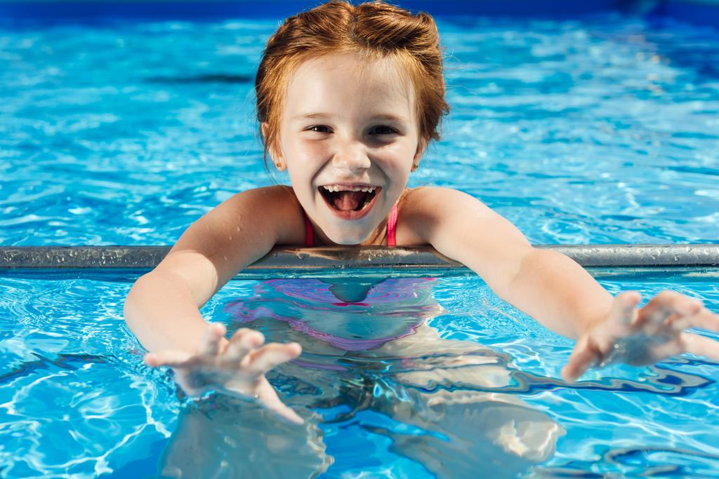 крупным планом портрет очаровательного ребенка в бикини в бассейне, смотрящего в камеру
 - Фото, изображение