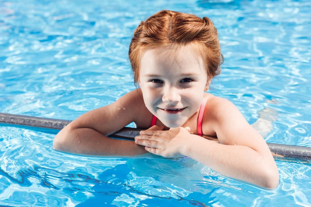 крупним планом портрет щасливої маленької дитини в бікіні в басейні дивиться на камеру
 - Фото, зображення