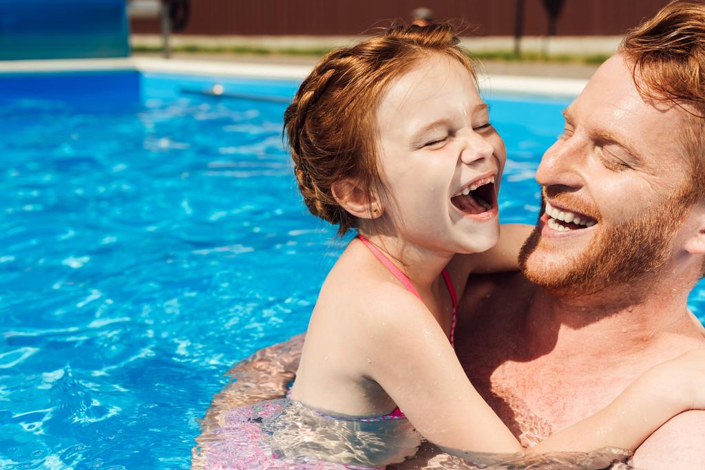 γελώντας ο πατέρας αγκαλιάζει την κόρη του λίγο χαμογελώντας στην πισίνα - Φωτογραφία, εικόνα