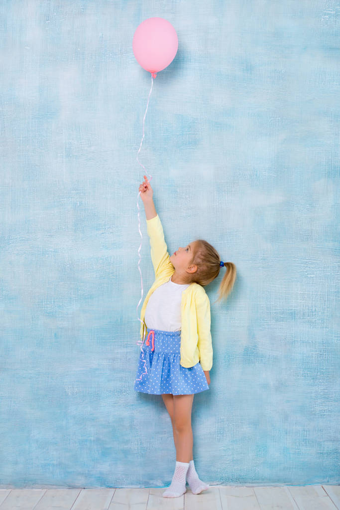 Celé délce. Roztomilá holčička drží růžové bubliny na modrém pozadí. - Fotografie, Obrázek