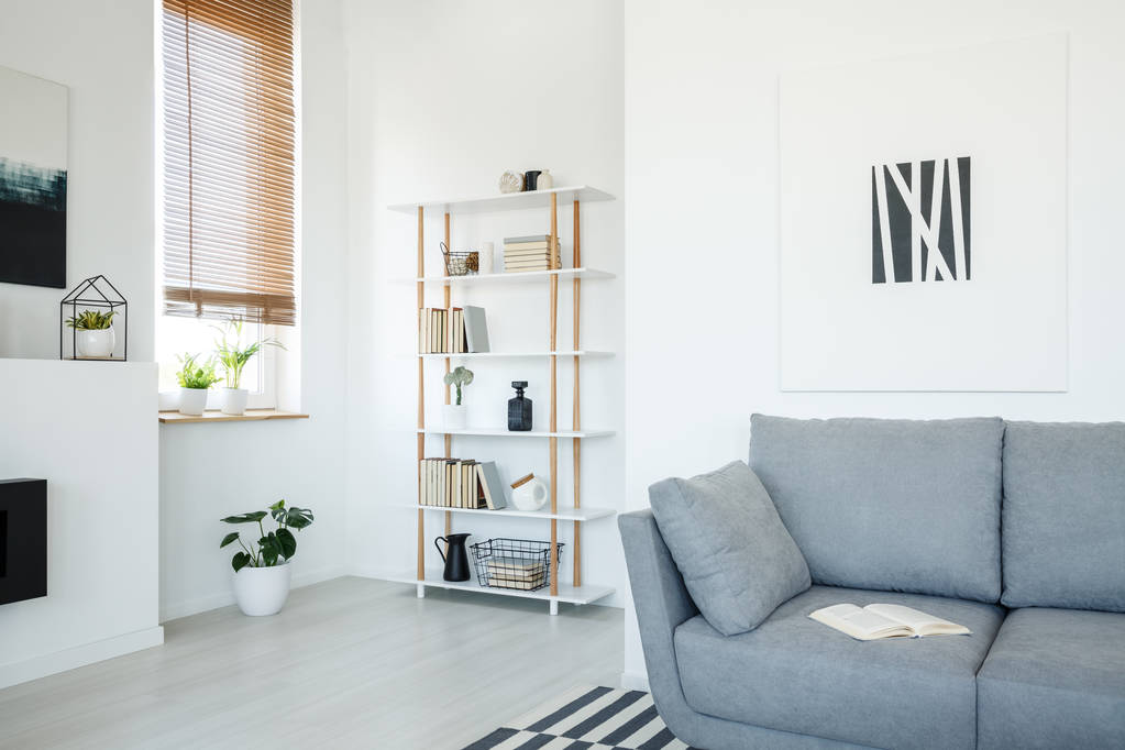Poster über grauem Sofa in weißem Wohnzimmerinterieur mit Pflanzen unter Fenster mit Jalousien. echtes Foto - Foto, Bild