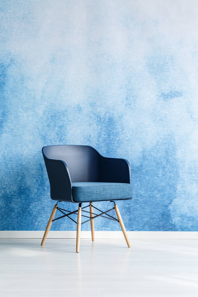 単一のモダンなネイビー ブルーの椅子オフィス室内で空の青と白のオンブル壁に立っています。領域をコピーします。実際の写真. - 写真・画像