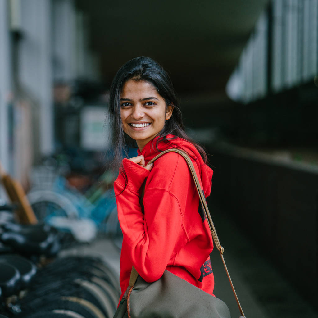 retrato de menina índia sorridente em pé no fundo com bicicletas estacionadas
 - Foto, Imagem
