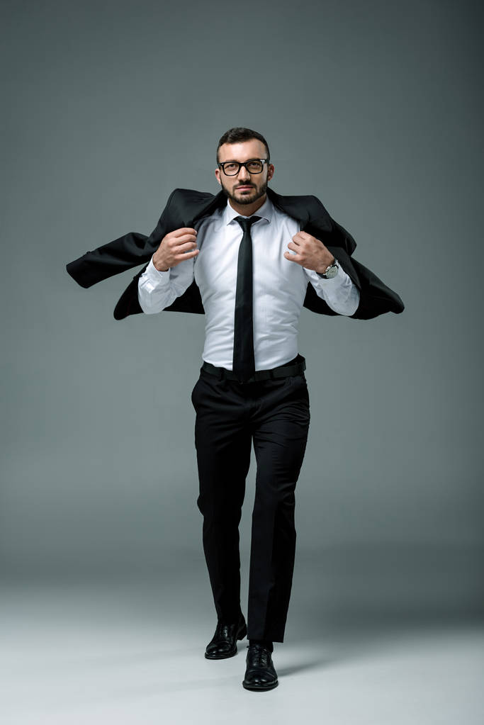 hombre de negocios guapo caminando y usando chaqueta en gris
 - Foto, Imagen