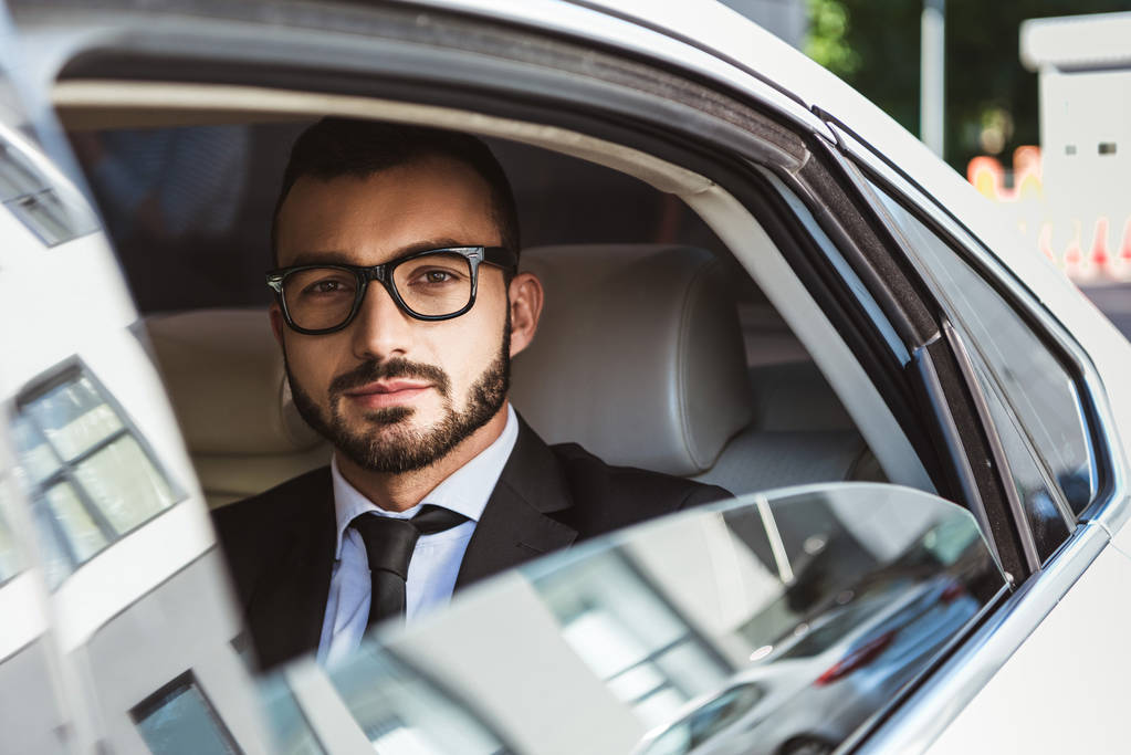handsome businessman sitting in car and looking at camera - Photo, Image