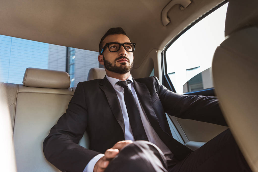 красивый бизнесмен в костюме сидит в машине
 - Фото, изображение