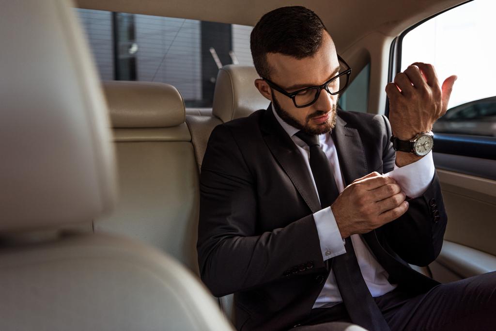 guapo hombre de negocios buttoning puño en coche
 - Foto, Imagen