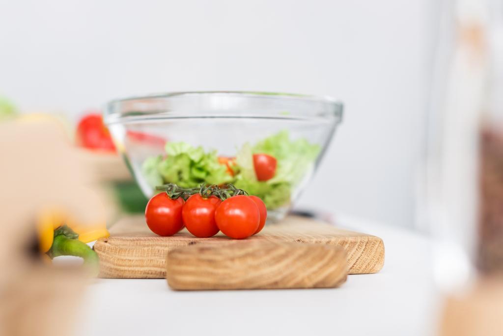 selective focus of glass bowl and fresh vegetables on wooden cutting board - Photo, Image