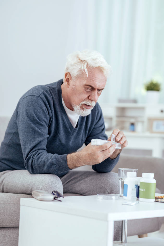 Homme âgé concentré comptant les pilules
 - Photo, image