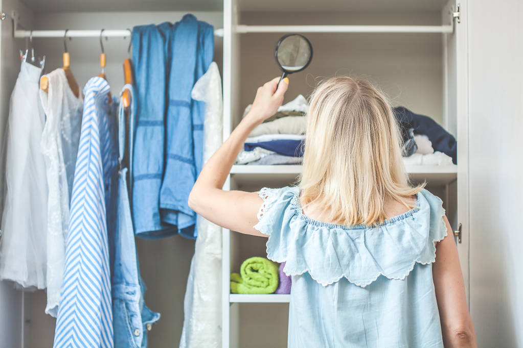девушка возле гардероба с одеждой смотрит с лупой, что ей надо надеть, а что нет
 - Фото, изображение