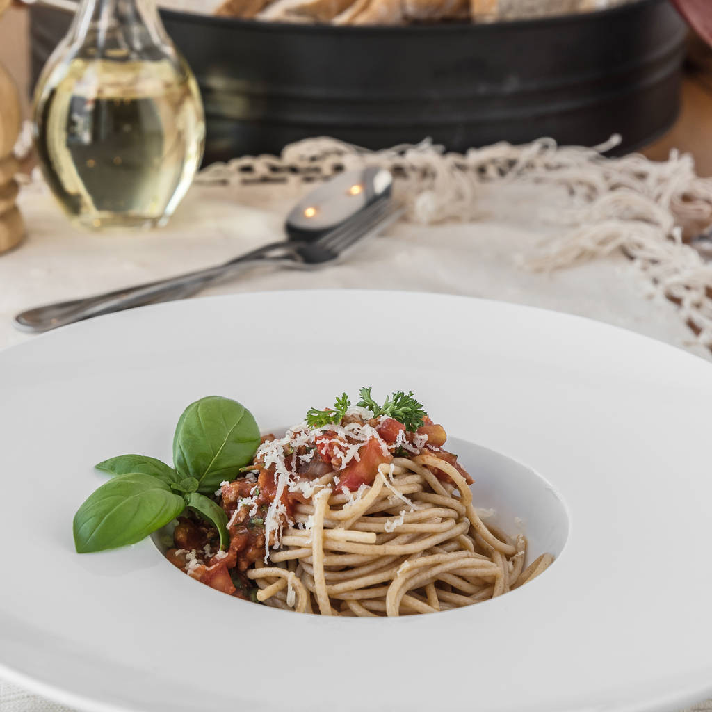 Placa de lof close-up de espaguete coberto com delicioso molho de bolonhesa e manjericão
 - Foto, Imagem