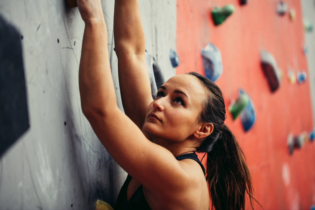Schöne junge starke Frau klettert auf rote künstliche Wand Draufsicht. - Foto, Bild