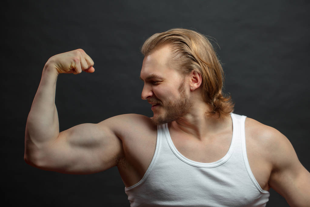 cheerful sporty male looking at his muscular arm - Photo, Image