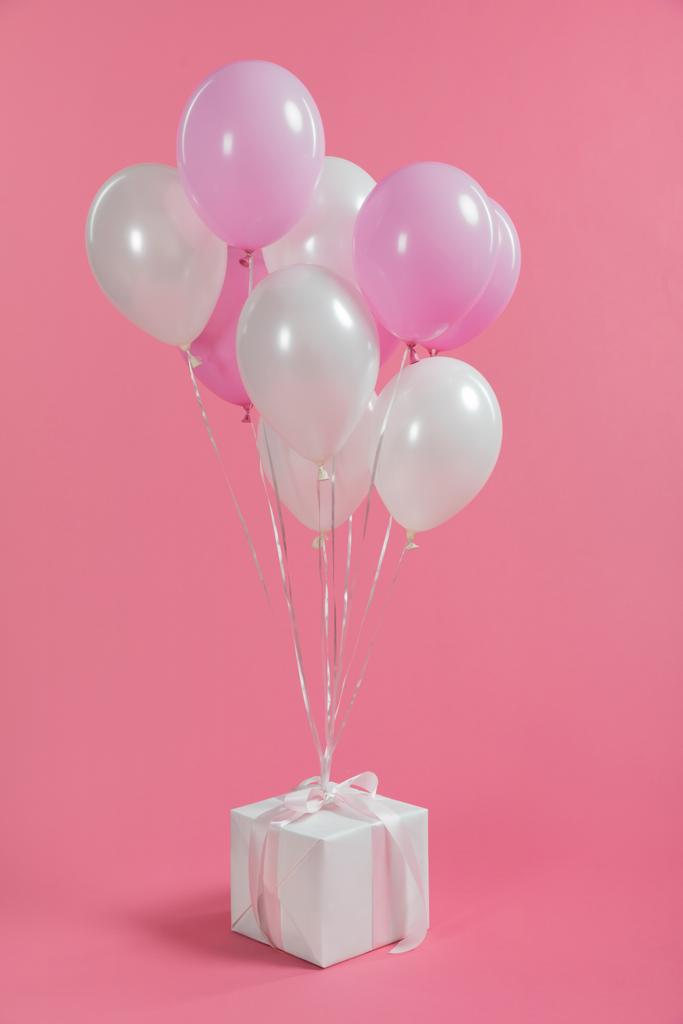 Manojo de globos atados en caja de regalo sobre fondo rosa
 - Foto, Imagen