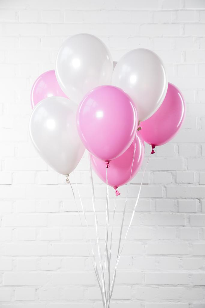 Μάτσο ροζ και λευκά μπαλόνια σε φόντο λευκό τούβλο τοίχο - Φωτογραφία, εικόνα