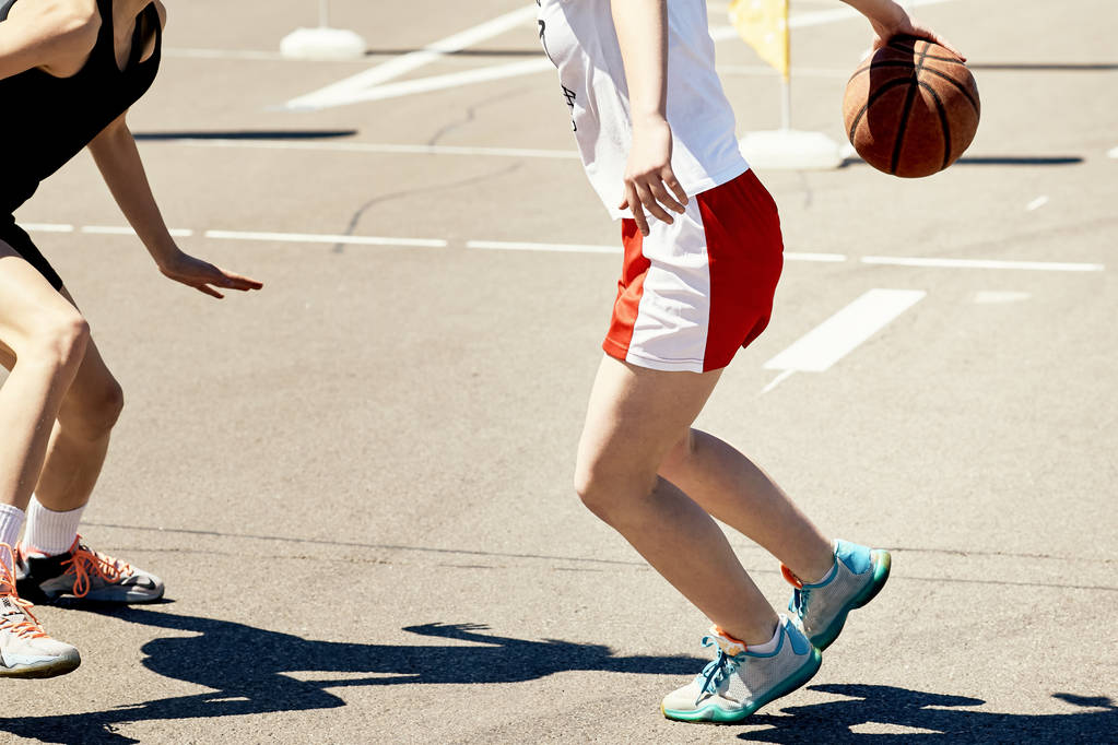 Dwie nastoletnie dziewczyny gry w koszykówkę w parku na boisko sportowe. - Zdjęcie, obraz