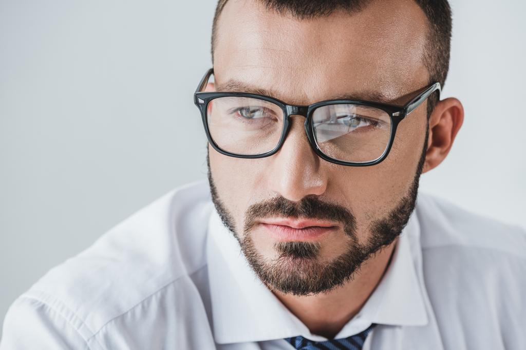 портрет красивого бизнесмена в очках, смотрящего вдаль изолированным на белом
 - Фото, изображение