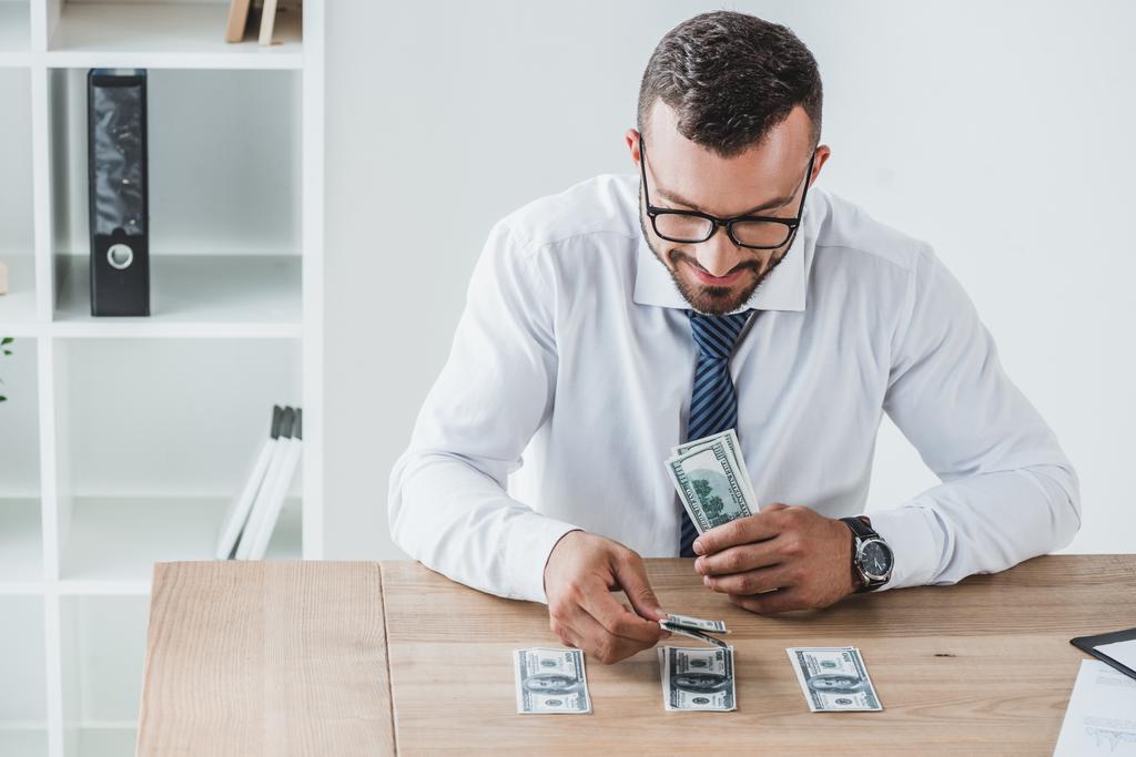 Красивый финансист, считая долларовые банкноты на столе в офисе
 - Фото, изображение