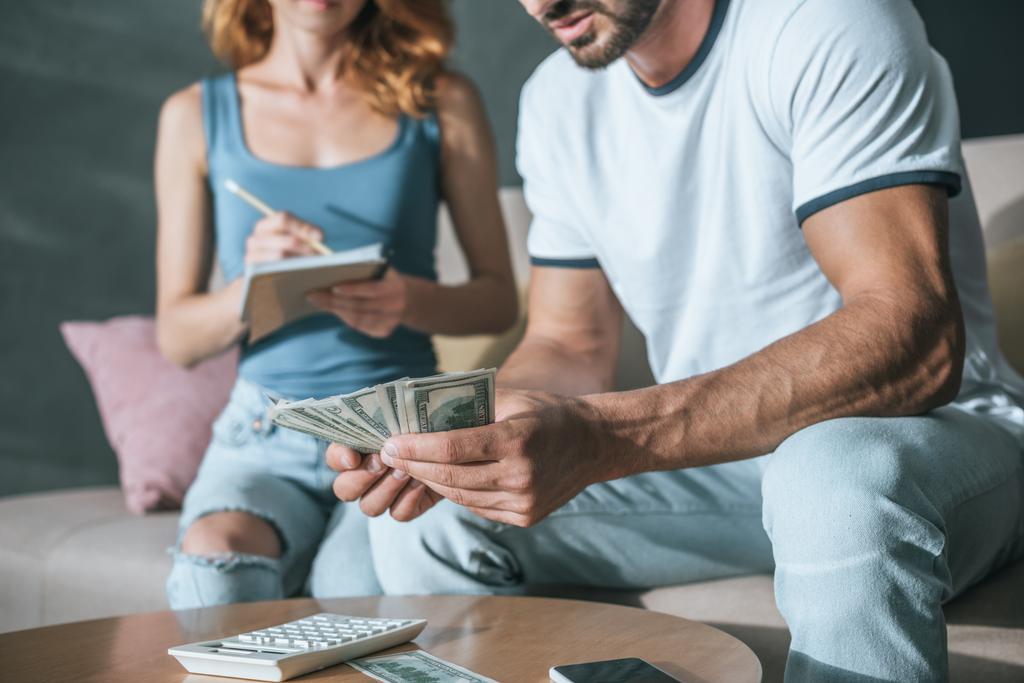 abgeschnittenes Bild eines Paares, das sein Familienbudget plant und Geld im Wohnzimmer zählt - Foto, Bild