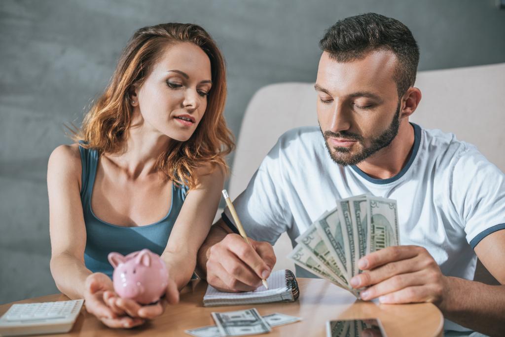 Paar plant Familienbudget mit Sparschwein und Dollars im Wohnzimmer - Foto, Bild
