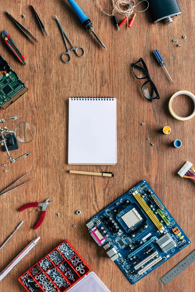 Draufsicht auf leeres Lehrbuch und Stift mit Reparaturwerkzeugen und Motherboard auf Holztisch - Foto, Bild