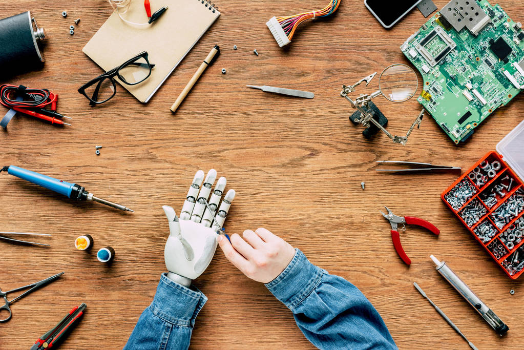 περικομμένη εικόνα του ανθρώπου τον καθορισμό ρομποτικό χέρι με κατσαβίδι στο ξύλινο τραπέζι - Φωτογραφία, εικόνα