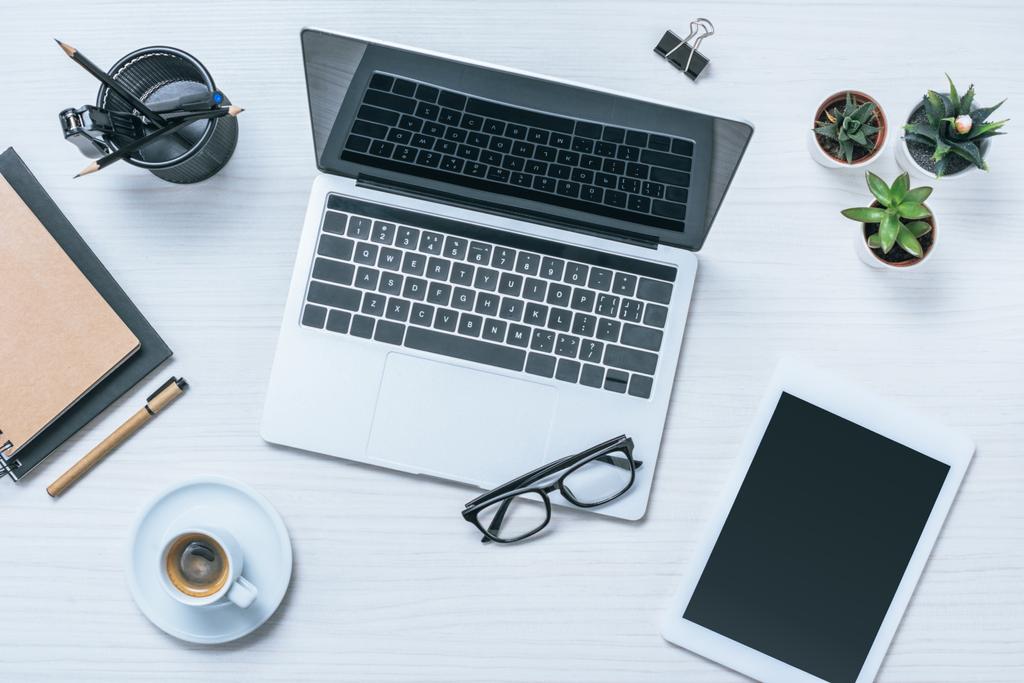 erhöhter Blick auf den Geschäftsmann-Arbeitsplatz mit Kaffeetasse, digitalem Tablet und Laptop auf dem Tisch - Foto, Bild