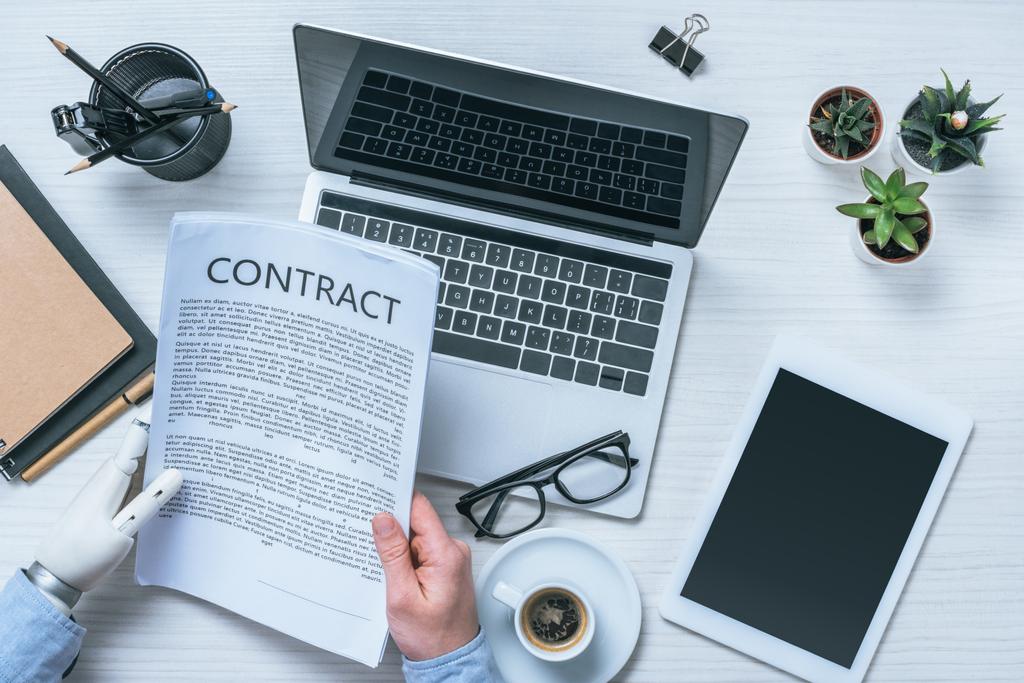 обрезанный имидж бизнесмена с контрактом на чтение протезов рук за столом в офисе
  - Фото, изображение