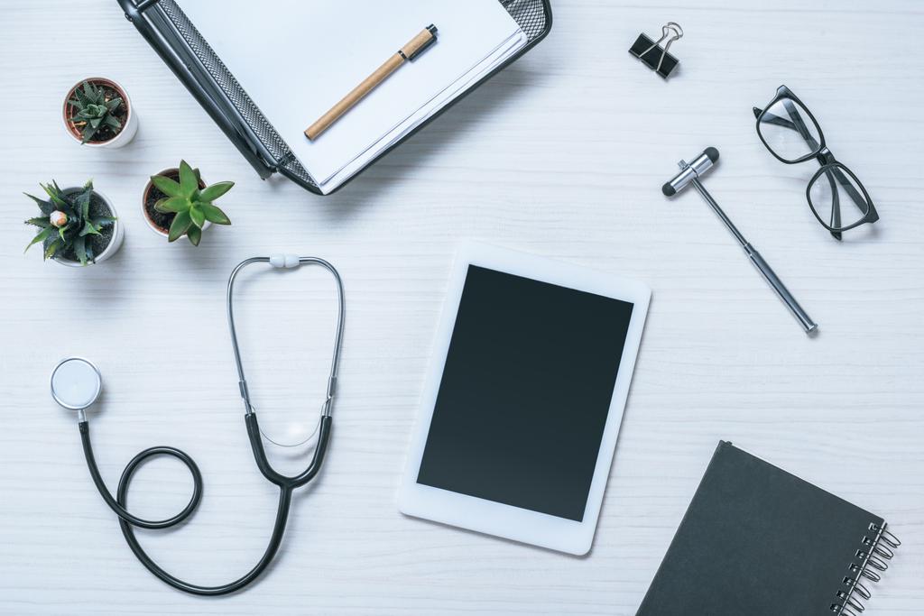 podwyższone widok miejsca pracy lekarza z podręcznika, stetoskop, młotek neurologiczny i cyfrowego tabletu na stole  - Zdjęcie, obraz