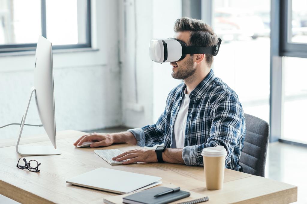 jovem em realidade virtual headset usando computador desktop no local de trabalho
   - Foto, Imagem