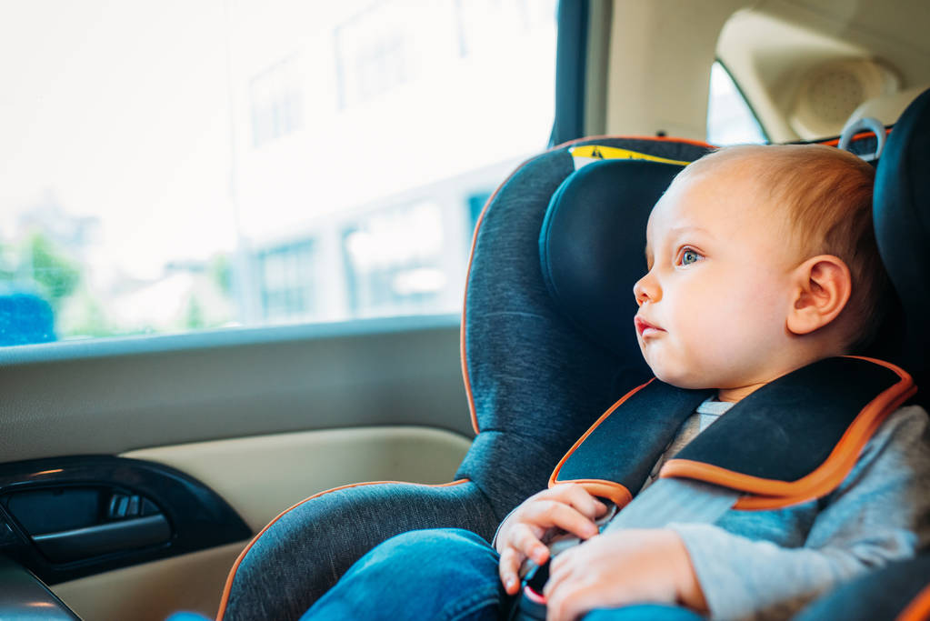 adorable little baby sitting in child safety seat in car and looking through window - Photo, Image