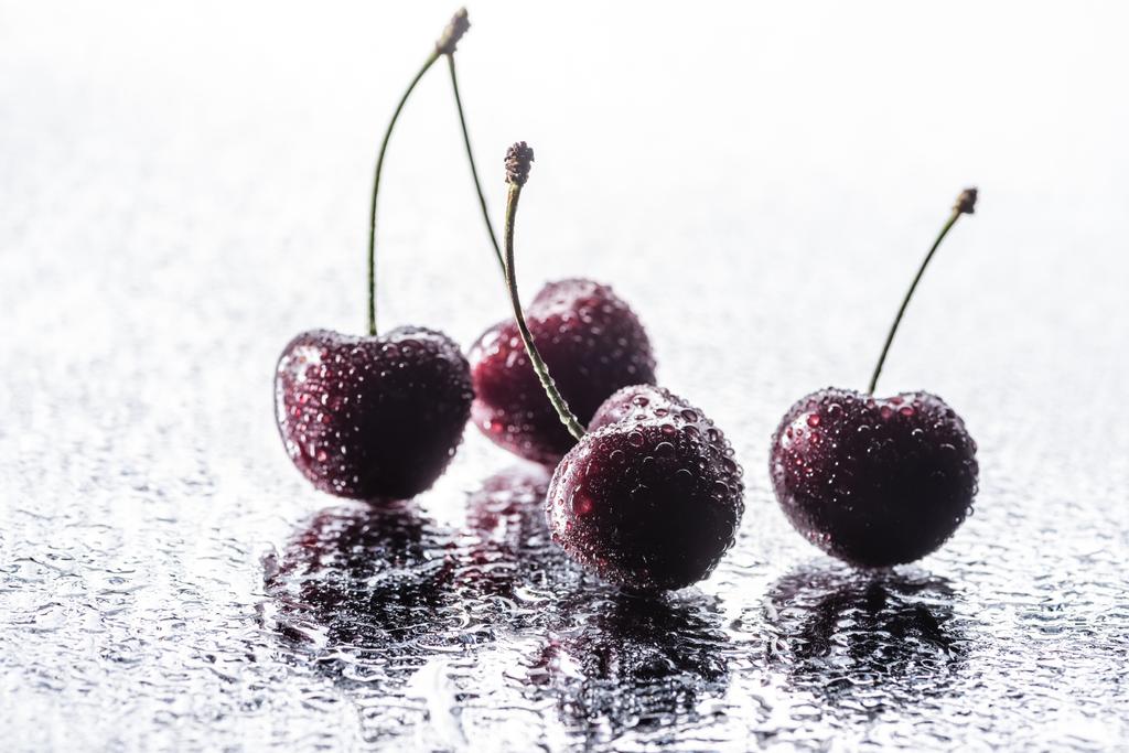 close up view of red ripe cherries with water drops on wet surface  - Photo, Image