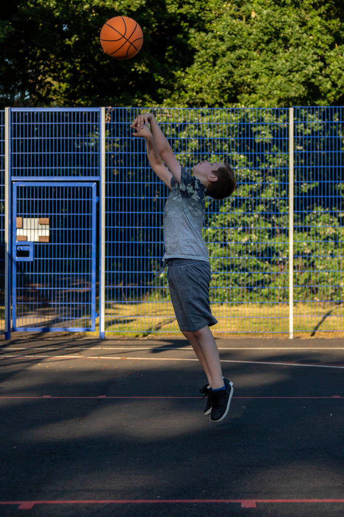 Niño preadolescente jugando con un baloncesto en un parque
 - Foto, Imagen