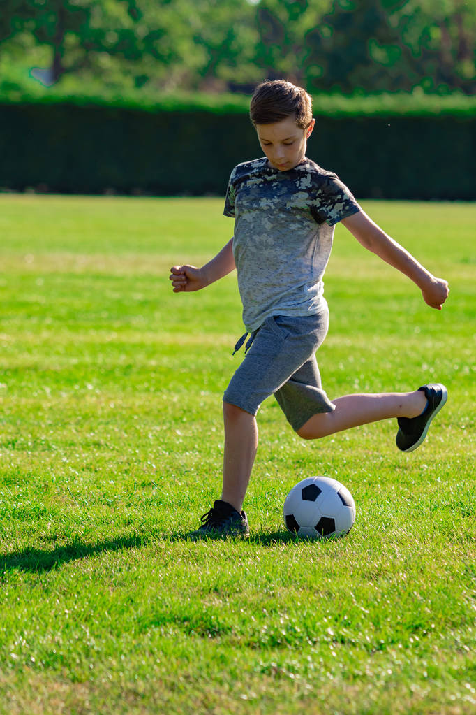 Pré-adolescent garçon jouer au football dans un parc
 - Photo, image
