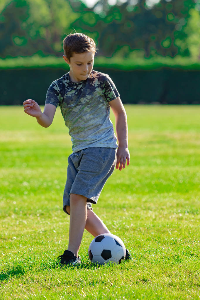 Előre tini fiú futballozni egy parkban - Fotó, kép