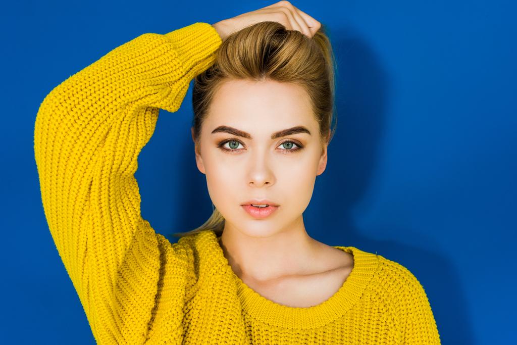 Žena modelka ve žlutém svetru pózuje na modrém pozadí - Fotografie, Obrázek