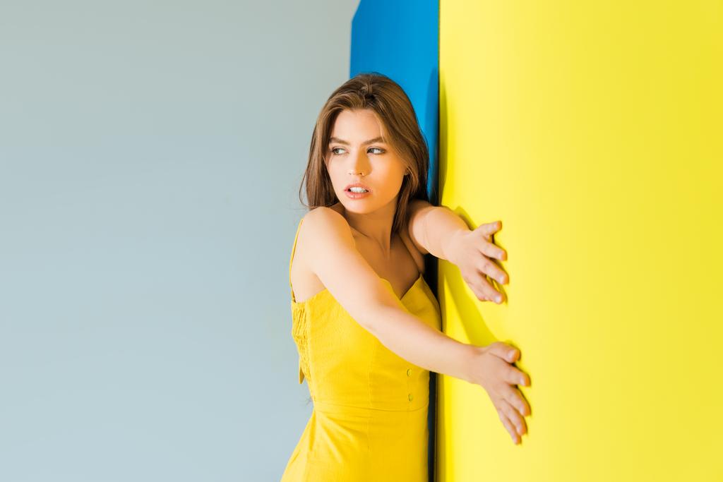 weibliche Mode-Modell steht zu blauem und gelbem Hintergrund - Foto, Bild