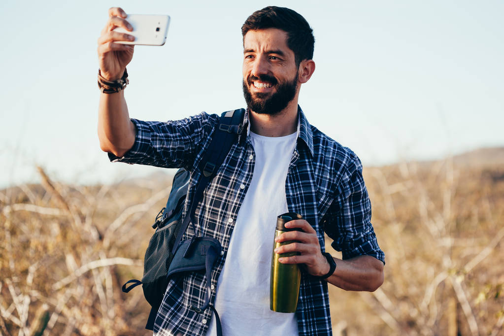 Muž s batohem, přičemž selfie s jeho mobilním telefonem během pouštní túry - Fotografie, Obrázek