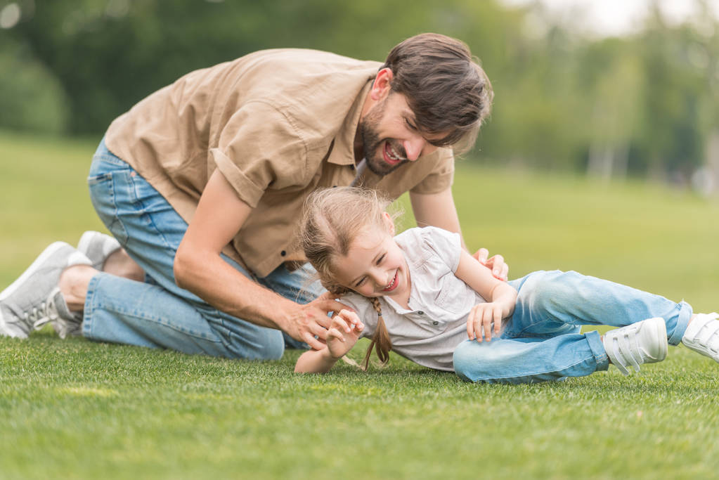 felice padre e figlia si divertono insieme sul prato verde nel parco
 - Foto, immagini