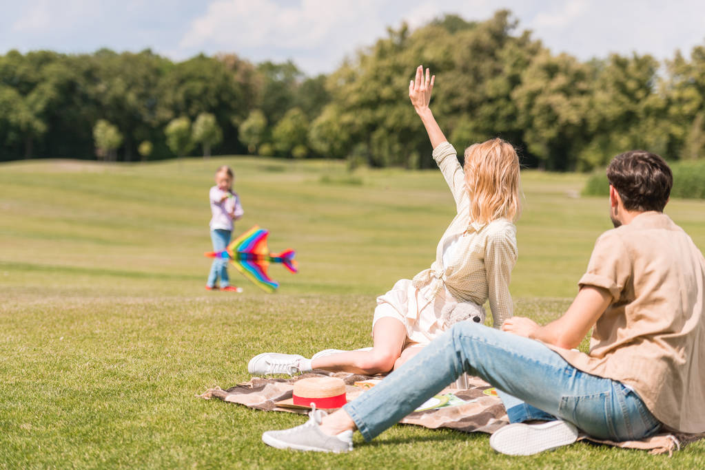 カラフルな凧で遊んで、ピクニックで座っている親を見て子 - 写真・画像