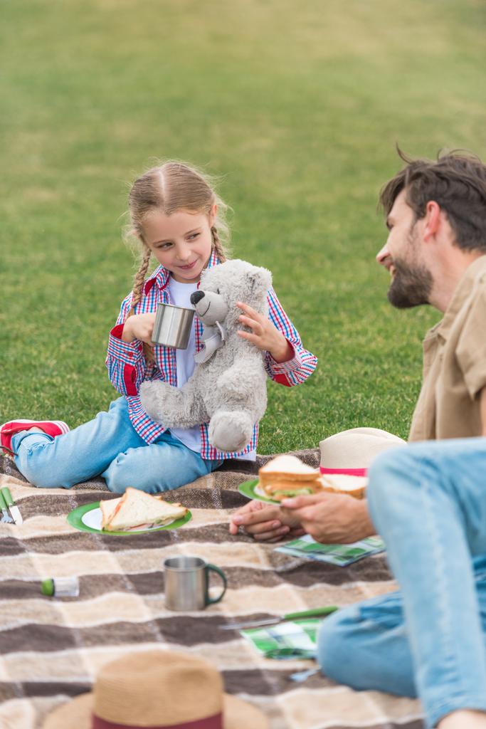 boldog apa és lánya mosolyogva egymást, miközben piknik a parkban  - Fotó, kép