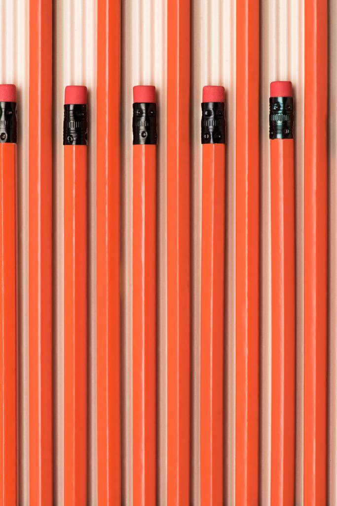 vista superior de lápices de grafito rojo con gomas de borrar colocadas en fila en beige
  - Foto, Imagen