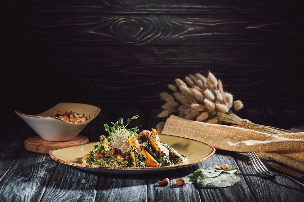 samenstelling van de levensmiddelen van panikesh met spinazie en kom met cashewnoten op houten tafel  - Foto, afbeelding