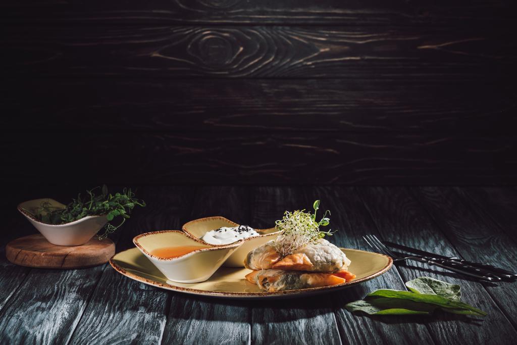 samosas em massa de phyllo recheada com espinafre e paneer decorado com sementes germinadas de alfafa e girassol em prato com molhos
  - Foto, Imagem