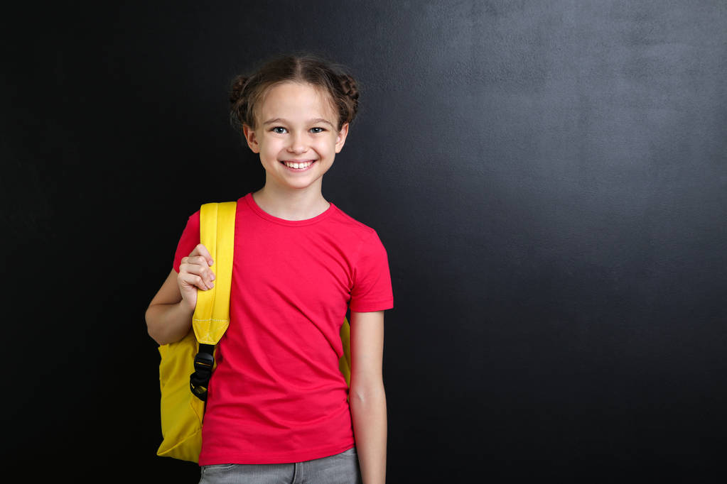 Молодая девушка с рюкзаком на фоне доски
 - Фото, изображение