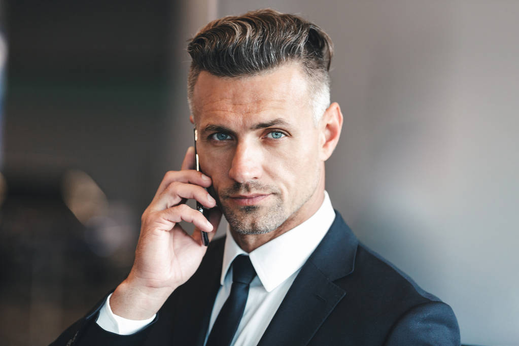 Vertrouwen rijpe zakenman praten op mobiele telefoon terwijl je in de lobby van de luchthaven - Foto, afbeelding