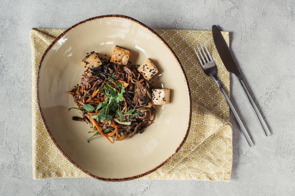 харчова композиція з собою з тофу та овочами, прикрашеними пророщеним насінням соняшнику на сірій тарілці
 - Фото, зображення